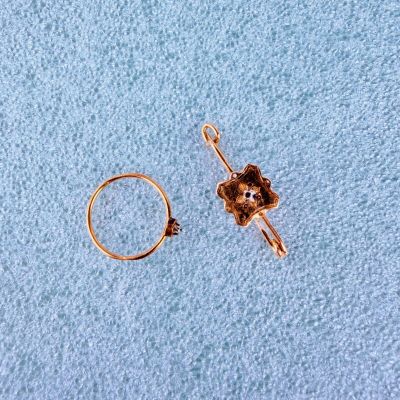 une bague en or ornée d'une fleur, à côté d'une autre bague en or ornée d'une fleur