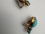 pair of turquoise and gold earrings on a white surface