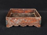 an old wooden box with carvings on it sitting on a black surface