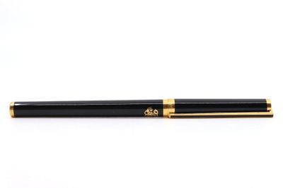 un stylo à bille noir et doré posé sur une surface blanche