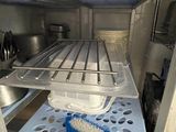a blue brush sitting in the bottom of an open refrigerator