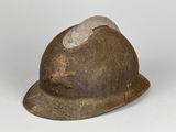 un vieux casque qui a été porté par un homme et sur lequel se trouve un chapeau