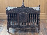a wooden crib with carvings on it on a wooden floor