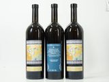 trois bouteilles de vin posées les unes à côté des autres sur une surface blanche