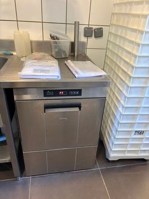 un lave-vaisselle dans une cuisine où il y a beaucoup de vaisselle sur le plan de travail