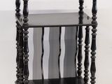 une petite table noire avec un plateau en verre, montée sur roulettes