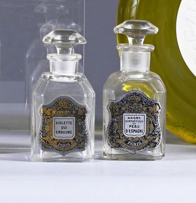 three bottles of perfume sitting on a counter next to a clock