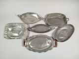 several silver dishes and trays on a white surface