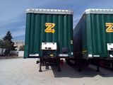 two green semi trailers parked next to each other in a parking lot