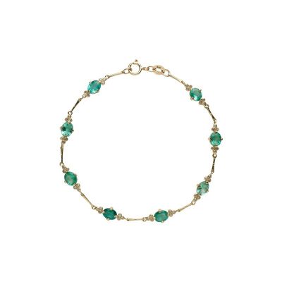 un bracelet en or orné de perles de verre vertes sur fond blanc
