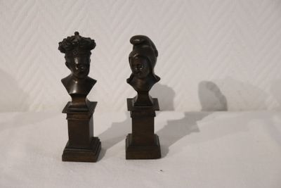 une paire de bustes en bronze représentant une femme et un homme, posés sur des socles