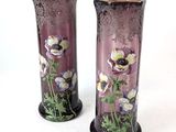 two vases with flowers painted on them sitting on a table
