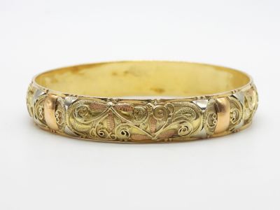 un gros plan d'un bracelet en or sur une surface blanche