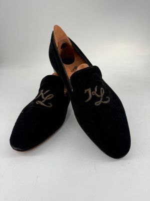 chaussons en velours noir ornés de monogrammes dorés sur la pointe