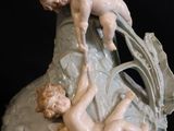 a vase with a statue of two cherensils on it