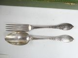 two silver spoons and a fork on a table