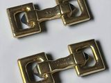 pair of brass plated buckles on a white surface