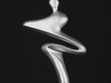 une sculpture en argent représentant une femme debout sur une surface noire