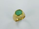 gros plan d'une bague en or avec une pierre verte
