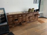 une grande armoire en bois munie de tiroirs et sur laquelle est apposée une pancarte