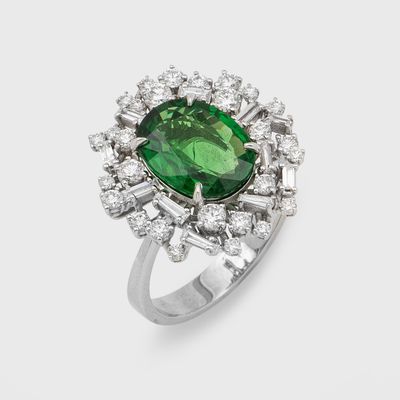 a close up of a ring with a green stone surrounded by white diamonds