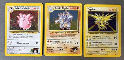 trois cartes Pokémon aux motifs différents posées sur une table