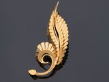 an image of a gold leaf brooch on a black surface