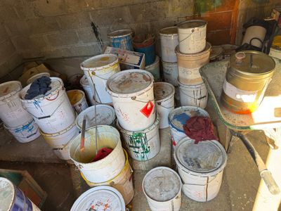 many buckets of paint sitting on the floor in a room