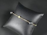 a black pillow with a gold chain and pearls on it