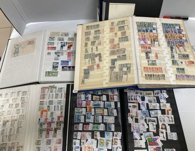 de nombreux timbres posés sur une table, à côté d'un livre ouvert