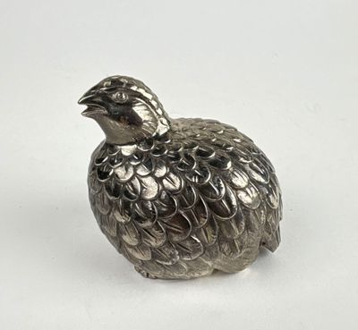 a silver figurine of a bird on a white surface