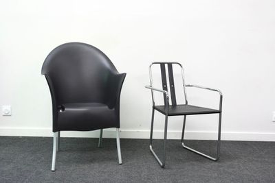 une chaise noire et une autre chaise noire, l'une à côté de l'autre