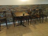 tables and chairs in a room with a brick wall behind them