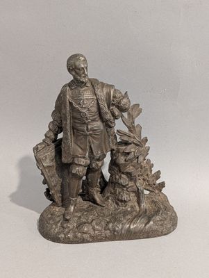 statue représentant un homme avec un chien et un chat, assis sur un rocher