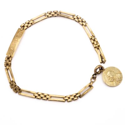 Gros plan sur un bracelet en or orné d'une pièce de monnaie
