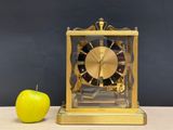 an apple next to a golden clock on a table