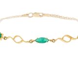 un bracelet en or orné de pierres vertes sur fond blanc