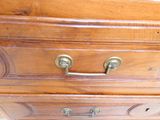 a wooden chest of drawers with brass handles and knobs