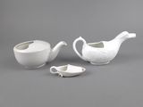 two white porcelain teapots and a saucer on a gray surface