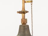 a large bell hanging from a chain on a white wall