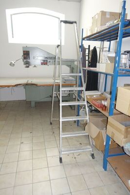 une pièce avec une échelle, des étagères et des cartons posés par terre