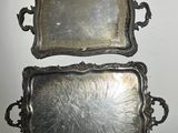two silver trays sitting on top of a table next to each other