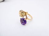 a close up of a gold ring with a purple stone