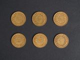 a close up of six gold coins on a black surface