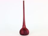 un vase rouge posé sur une surface blanche