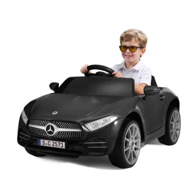 un petit garçon au volant d'une Mercedes de sport noire, portant des lunettes de soleil