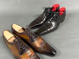 two pairs of brown shoes with red soles on a gray surface