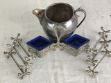 a silver pitcher sitting on a table next to a set of blue glass coasters