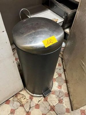 une poubelle dans un coin de la cuisine, sur laquelle est collée une étiquette jaune