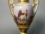 a gold vase with a painting of horses on it